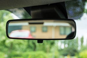Rear-view mirror in a car in green environment in UK residential area